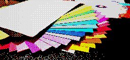 An image depicting a stack of paper with various bright colors sitting on a desk.